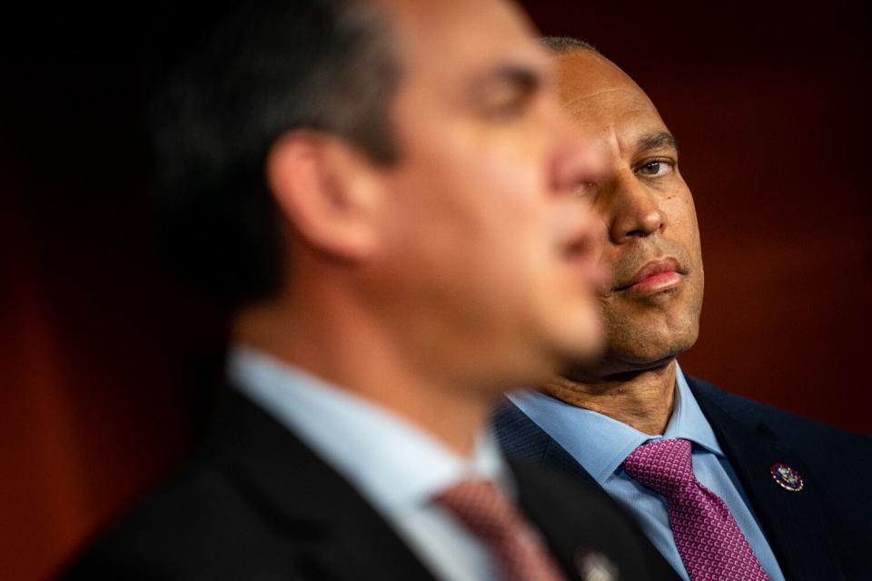 A closeup of two men in ties and jackets, focused on the one farther away as he looks at the other