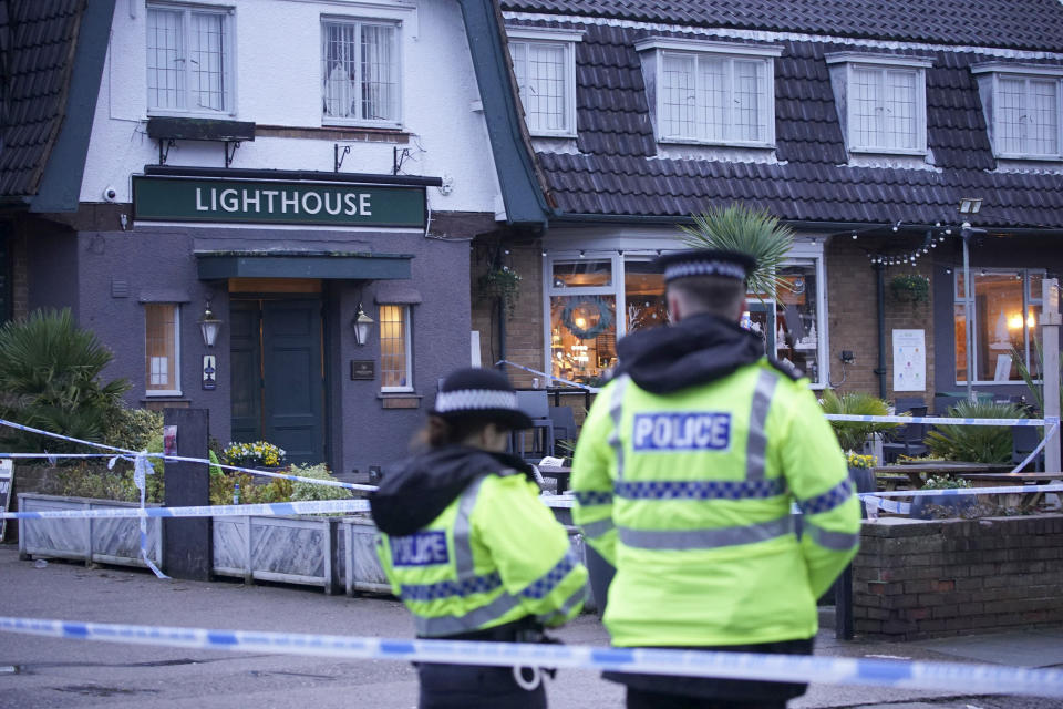 Police officers stand on duty at the Lighthouse Inn in Wallasey Village, near Liverpool, England, Sunday, Dec. 25, 2022. A Christmas Eve shooting at a pub in northwest England killed a young woman and wounded three men, police said Sunday. The Merseyside Police force said it was investigating the 11:50 p.m. Saturday shooting at the Lighthouse pub in the town of Wallasey as a murder case. Police have not detained any suspects. (Peter Byrne/PA via AP)