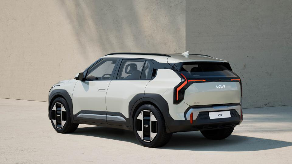 A Kia EV3 compact electric SUV is parked in front of a building.