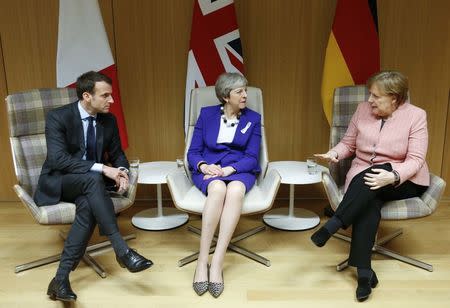 Britain's Prime Minister Theresa May is flanked by French President Emmanuel Macron and German Chancellor Angela Merkel before their trilateral meeting at the European Union leaders summit in Brussels, Belgium, March 22, 2018. REUTERS/Francois Lenoir/Pool