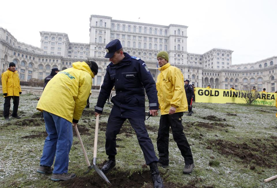 A Gendarme confiscates tools from Greenpeace activists who were digging into the yard of Romania's Parliament in Bucharest