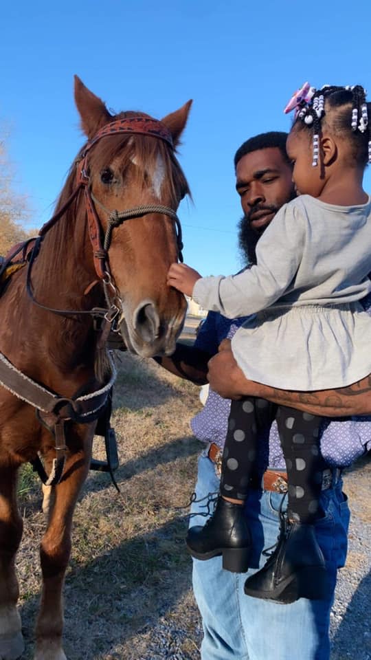 Ty Johnson shows a horse to a young girl at a birthday party.