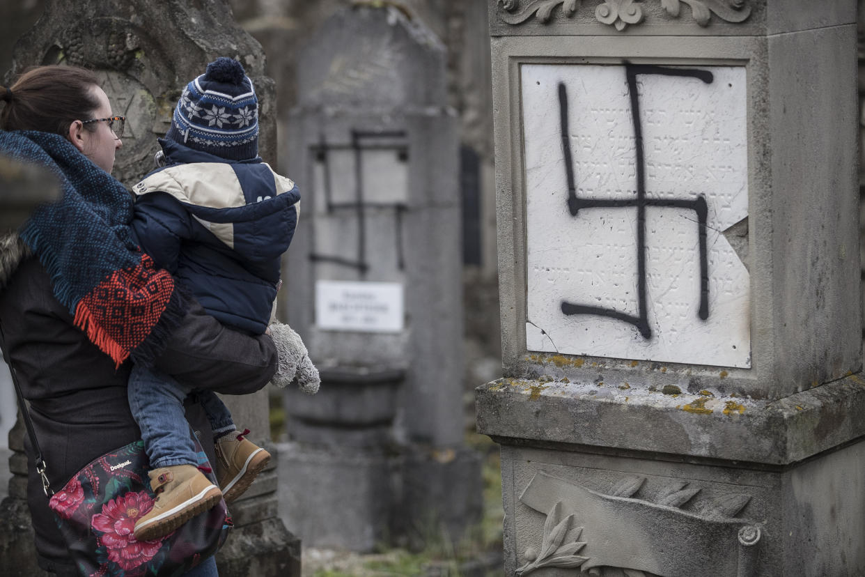 A woman stands in front of a desecrated tombstone.&nbsp; (Photo: ASSOCIATED PRESS)