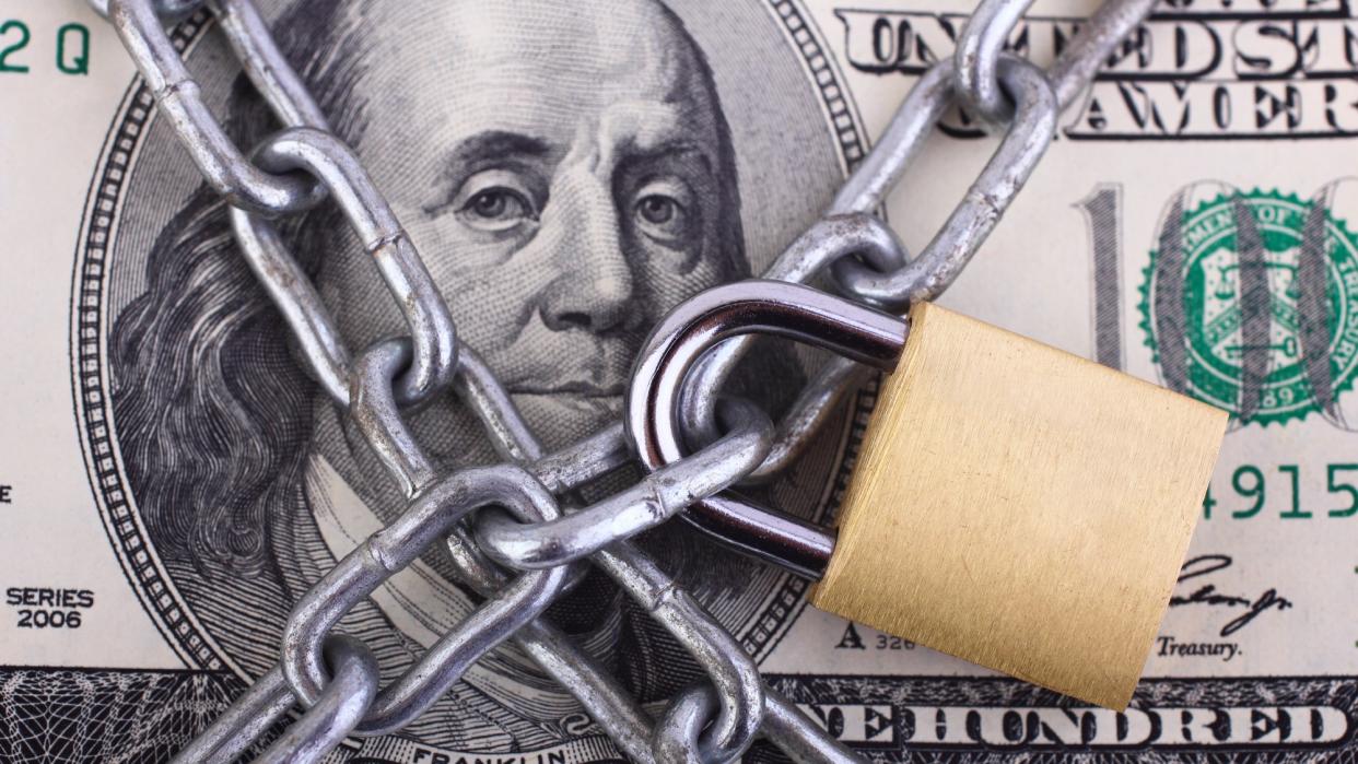  Padlock and chain wrapped around a hundred dollar bill. 