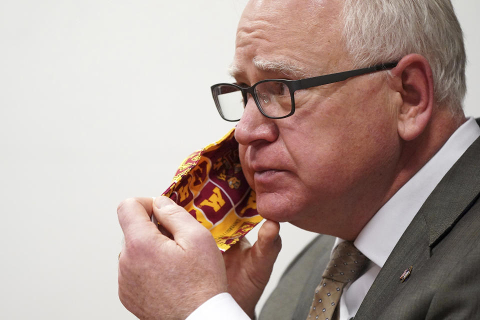 FILE - In this Jan. 26, 2021 file photo, Minnesota Gov. Tim Walz takes off his University of Minnesota cloth face mask to answer a question from a reporter during a press conference in St. Paul, Minnesota will lift nearly all its COVID-19 restrictions just before Memorial Day weekend and drop its statewide mask requirement once 70% of residents age 16 and older get their first dose of vaccine, but no later than July 1, Gov. Walz announced Thursday, May 6. (Anthony Souffle/Star Tribune via AP)