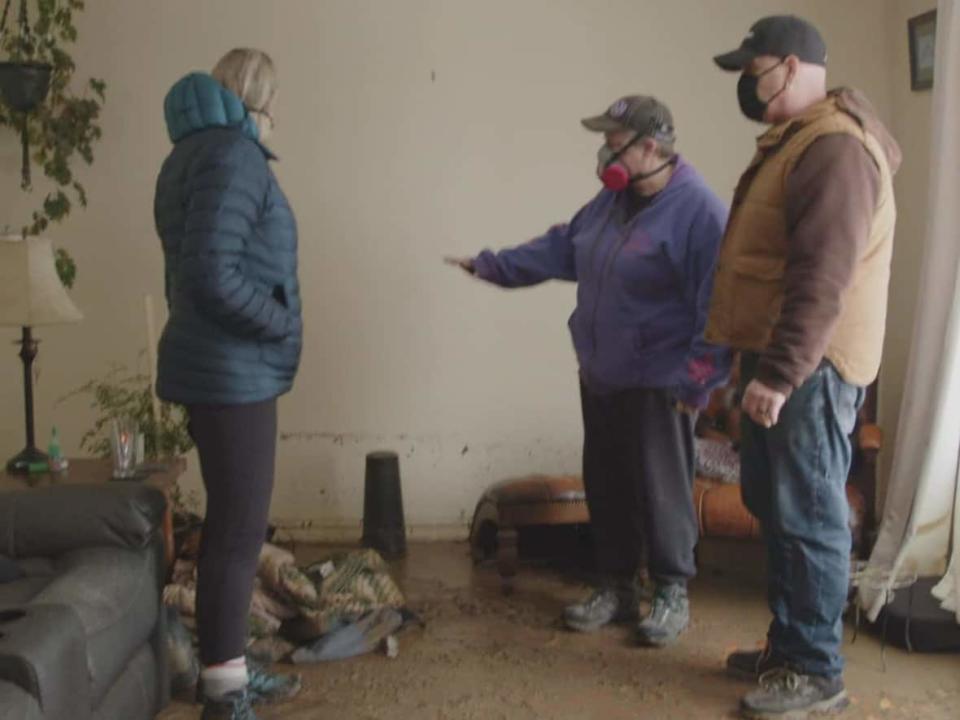 Michelle and James Hintz tour through what's left of their Merritt, B.C., home, pointing to water lines that show the flood waters came up around half a metre in their house.  (Georgie Smyth/CBC - image credit)