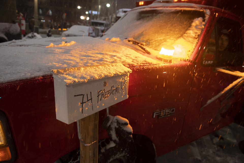 An amber strobe light illuminates snow falling on a protester's mailbox outside their pickup truck, on the 21st day of a protest against COVID-19 measures that has grown into a broader anti-government protest, on Thursday, Feb. 17, 2022, in Ottawa. (Justin Tang/The Canadian Press via AP)