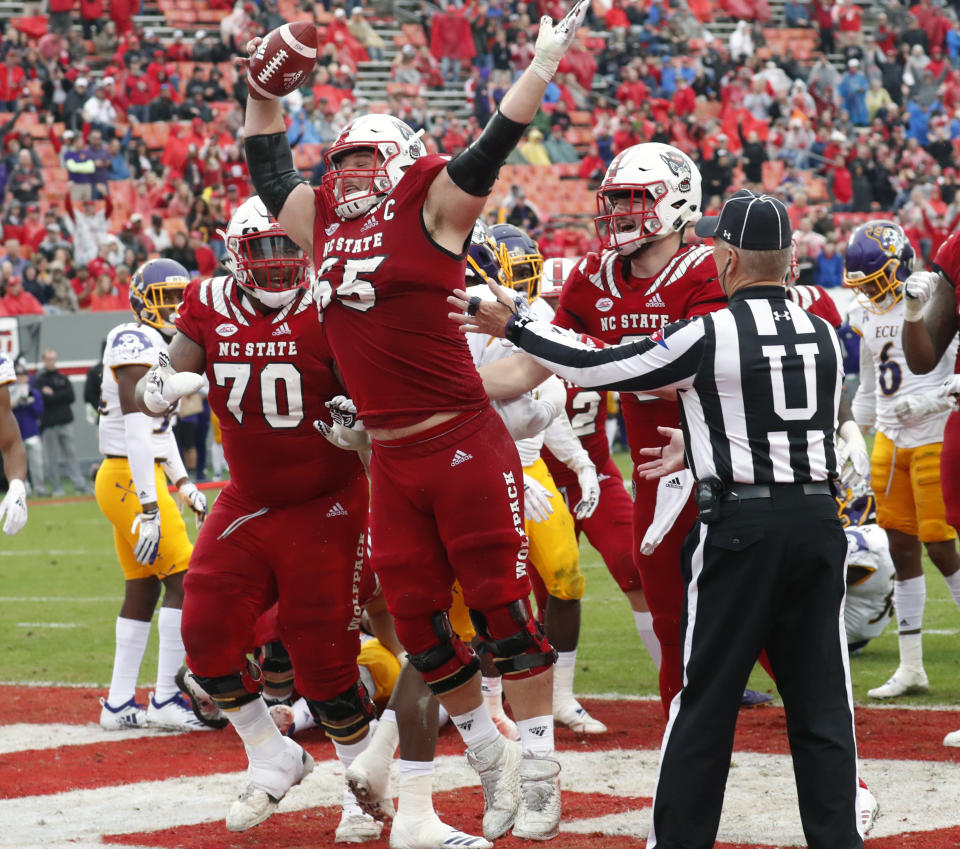 FILE - In this Dec. 1, 2018, file photo, North Carolina State center Garrett Bradbury (65) celebrates after he scored a touchdown during the second half of a game against East Carolina, in Raleigh, N.C. Bradbury was named to the 2018 AP All-America NCAA college football team, Monday, Dec. 10, 2018. (AP Photo/Chris Seward, File)
