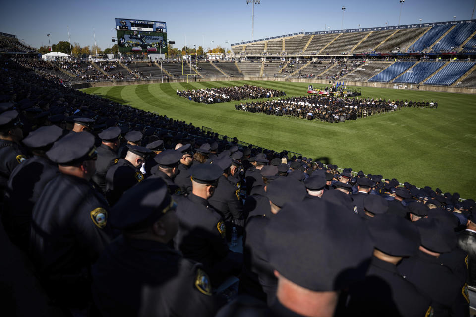 In this image provided by the Connecticut State Police Photo Unit, law enforcement personnel from across the country gather at the University of Connecticut's 40,000-seat stadium in East Hartford, Conn., Friday, Oct. 21, 2022, for the funeral of two officers shot to death in an apparent ambush. On Wednesday, Oct. 12, Nicholas Brutcher shot Bristol officers Dustin DeMonte, Alex Hamzy and Alec Iurato. Iurato survived the attack and killed Brutcher. Brutcher's brother was also shot and survived. A motive has not been disclosed. (Connecticut State Police Photo Unit via AP)