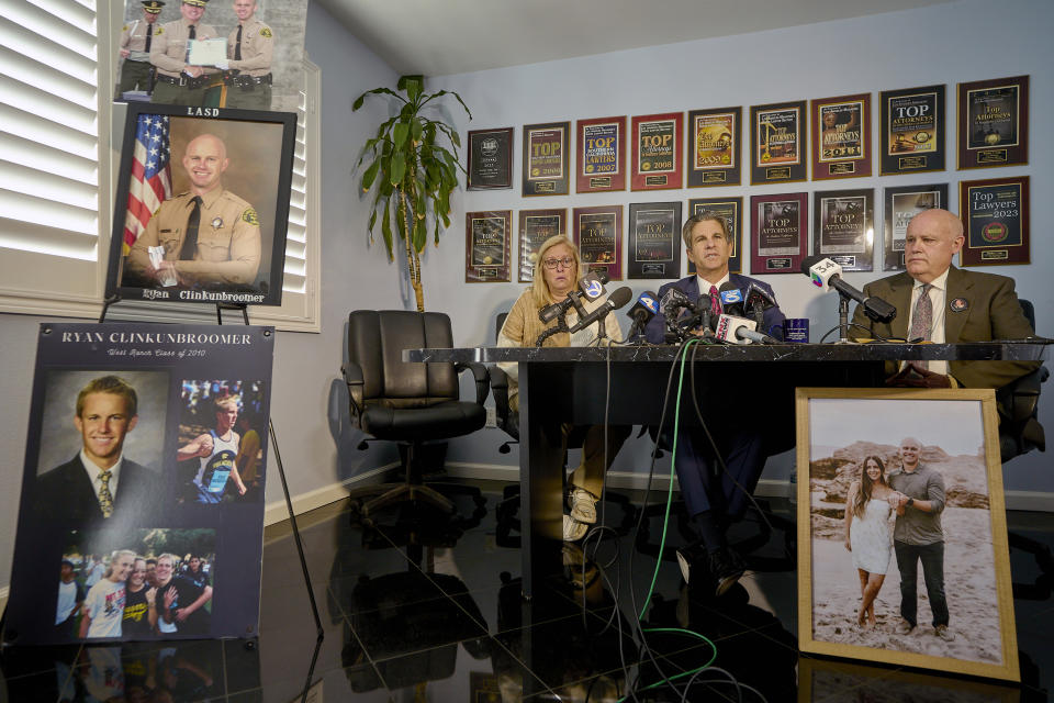 Attorney Bradley Gage, middle, and Kim and Mike Clinkunbroomer, the parents of late Los Angeles Sheriff's Deputy Ryan Clinkunbroomer, announce the precursor of a lawsuit against the Sheriff's Department at a news conference in Los Angeles on Tuesday, Nov. 28, 2023. Los Angeles County Sheriff's Deputy Clinkunbroomer was shot and killed Sept. 16, 2023, while sitting in his patrol car in Palmdale, Calif. His parents are seeking justice for their son and looking to make a change in LACSD's policies to protect other deputies from death. (AP Photo/Damian Dovarganes)