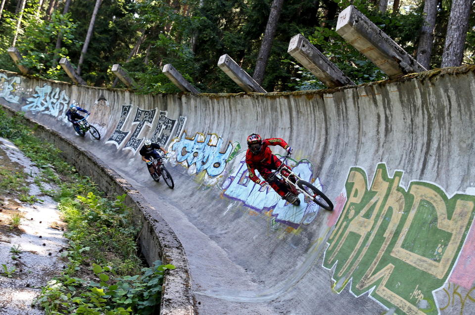 Downhill bikers Kemal Mulic (R-L), Tarik Hadzic and Kamer Kolar train on the disused bobsled track from the 1984 Sarajevo Winter Olympics, Aug. 8, 2015.