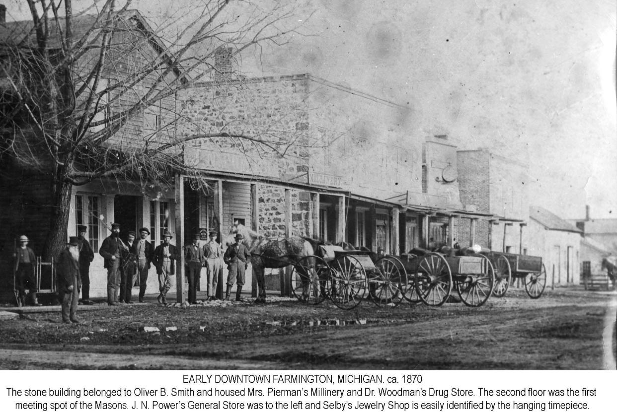 Early Downtown Farmington in 1870. The stone building belonged to Oliver B. Smith and housed Mrs. Pierman's Millinery and Dr. Woodmans' Drug Store. The second floor was the first meeting spot of the Masons. J.N. Power's General Store was to the left and Selby's Jewelry Shop's easily identified by the hanging timepiece.