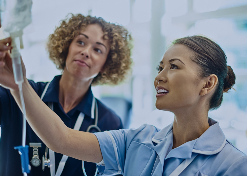 Two women nurses are looking at the ivy in front of them.