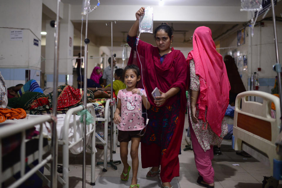 A child suffering from dengue is helped by a family member as she walks inside the dengue ward of Mugda Medical College and Hospital in Dhaka, Bangladesh, Thursday, Sept. 14, 2023. Bangladesh is struggling with a record outbreak of dengue fever, with experts saying a lack of a coordinated response is causing more deaths from the mosquito-transmitted disease. (AP Photo/Mahmud Hossain Opu)