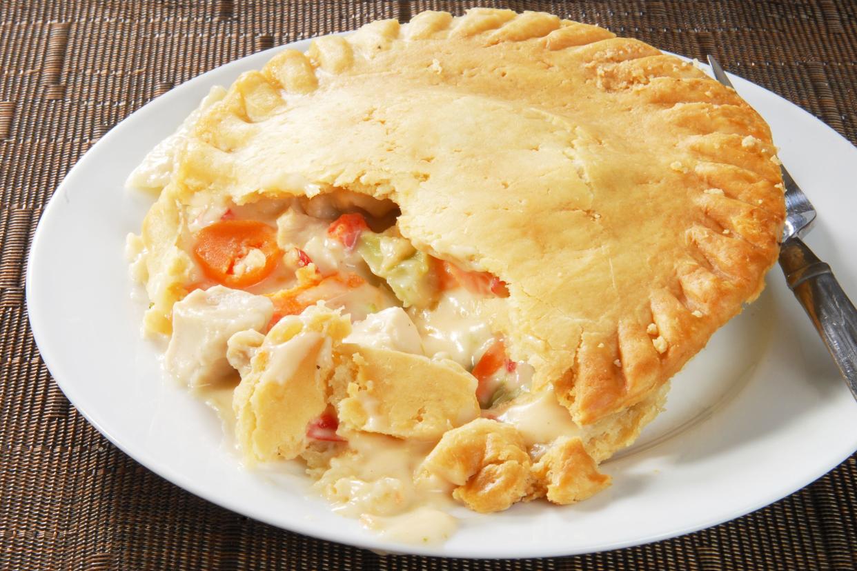 Favorite chicken potpie on a white plate with a knife on a brown table mat