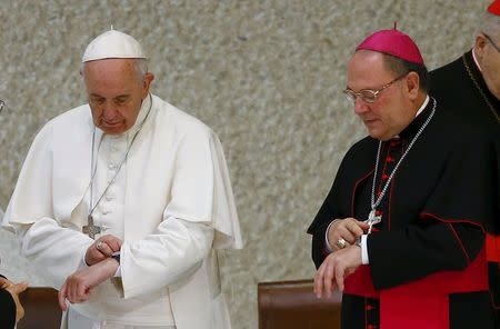 Pope Francis and an unidentified bishop look at their watches during a special audience to mark the 50th anniversary of Synod of Bishops in Paul VI hall at the Vatican October 17, 2015. REUTERS/Tony Gentile