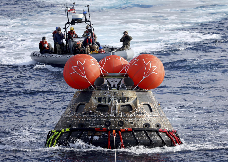 FILE - NASA's Orion capsule is drawn to the well deck of the USS Portland after it splashed down following a successful uncrewed Artemis I moon mission, Sunday, Dec. 11, 2022, in the Pacific Ocean off the coast of Baja California, Mexico. On Tuesday, Jan. 9, 2024, NASA said astronauts will have to wait until 2025 before flying to the moon and another few years before landing on it. (Mario Tama/Pool Photo via AP, File)