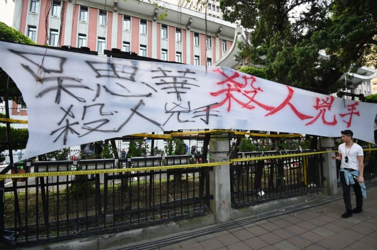 A protester walks past a banner reading "Education Minister Wu Se-hwa is a murderer" outside the Education Ministry in Taipei on July 31, 2015