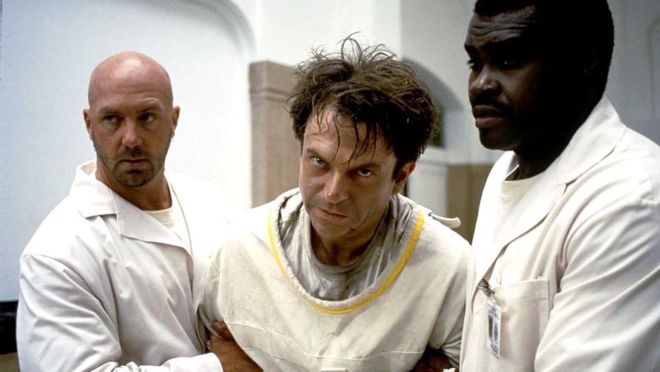 Sam Neill with disheveled hair in a straight jacket from the horror film In the Mouth of Madnes.