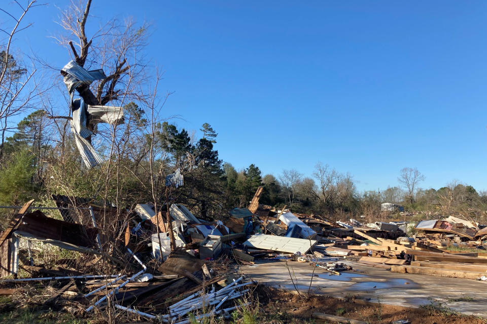 Debris, including twisted sheet metal wrapped around a treen, is strewn about following severe weather Wednesday, Dec. 14, 2022, in Keithville, La. A volatile storm ripping across the U.S. spawned tornadoes that killed a young boy and his mother in Louisiana, smashed mobile homes and chicken houses in Mississippi and threatened neighboring Southern states with more punishing weather Wednesday. (AP Photo/Jake Bleiberg)