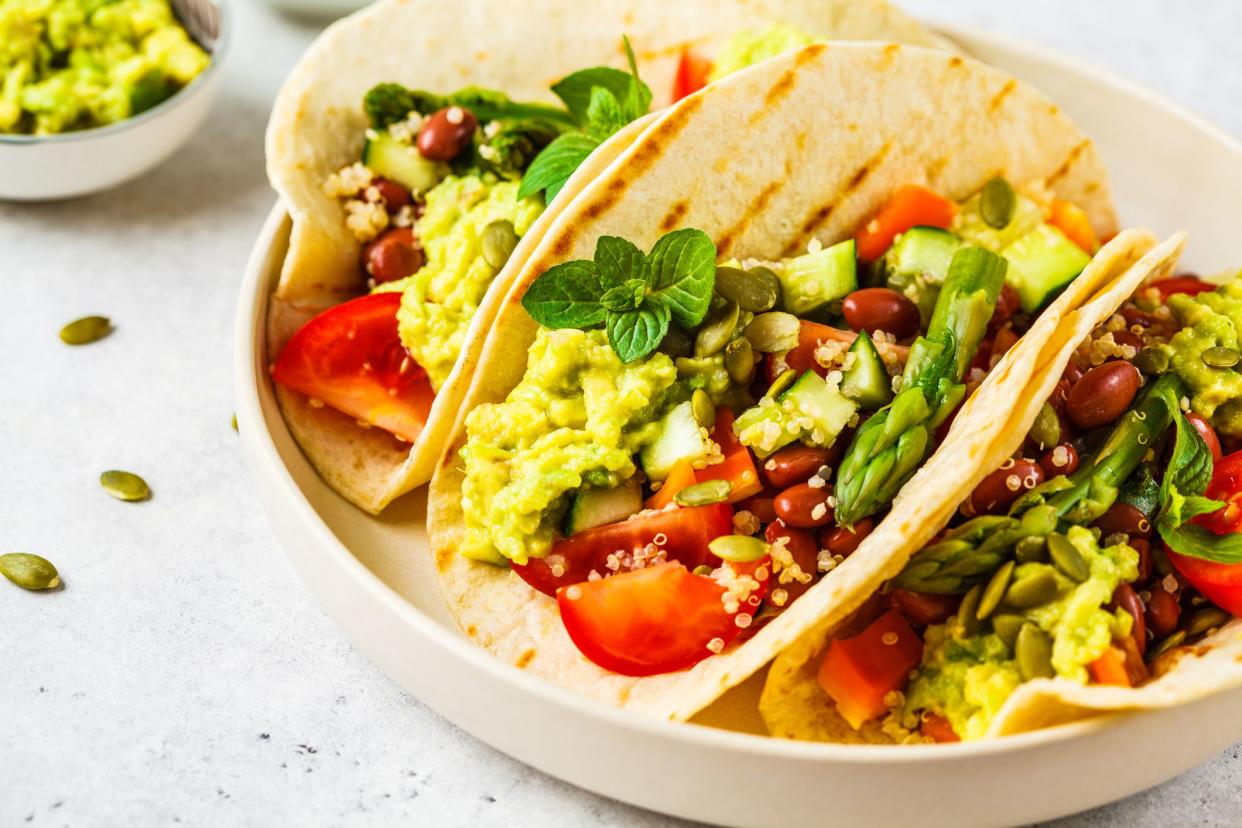 Vegan tortilla wraps with quinoa, asparagus, beans, vegetables and guacamole.