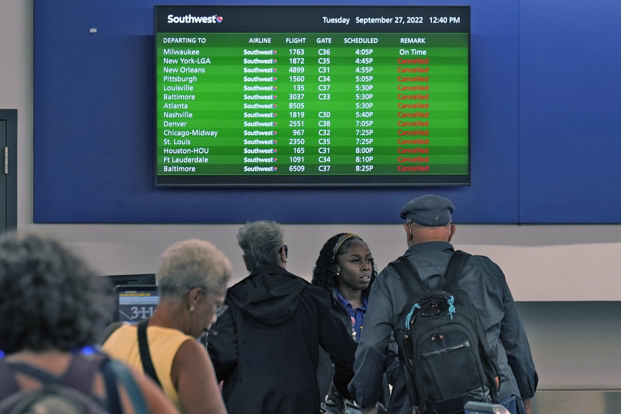 Southwest passengers and an employee try to deal with the flood of cancellations on Tuesday at Tampa International Airport.