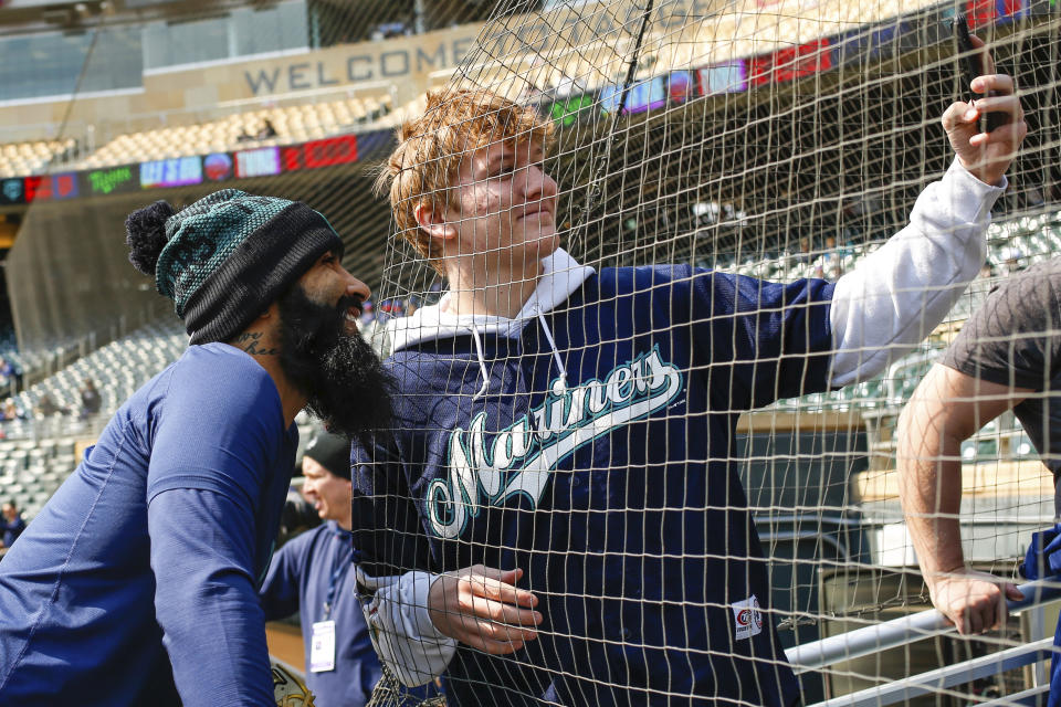 Seattle Mariners relief pitcher Sergio Romo poses for a selfie with a fan before a baseball game against the Minnesota Twins, Sunday, April 10, 2022, in Minneapolis. (AP Photo/Nicole Neri)