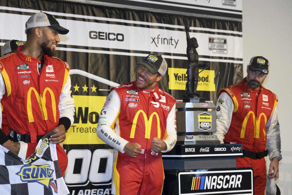 Bubba Wallace, center, celebrates with teammates as he stands next to the trophy after winning a NASCAR Cup series auto race Monday, Oct. 4, 2021, in Talladega, Ala. The race was stopped mid-race due to rain. (AP Photo/John Amis)