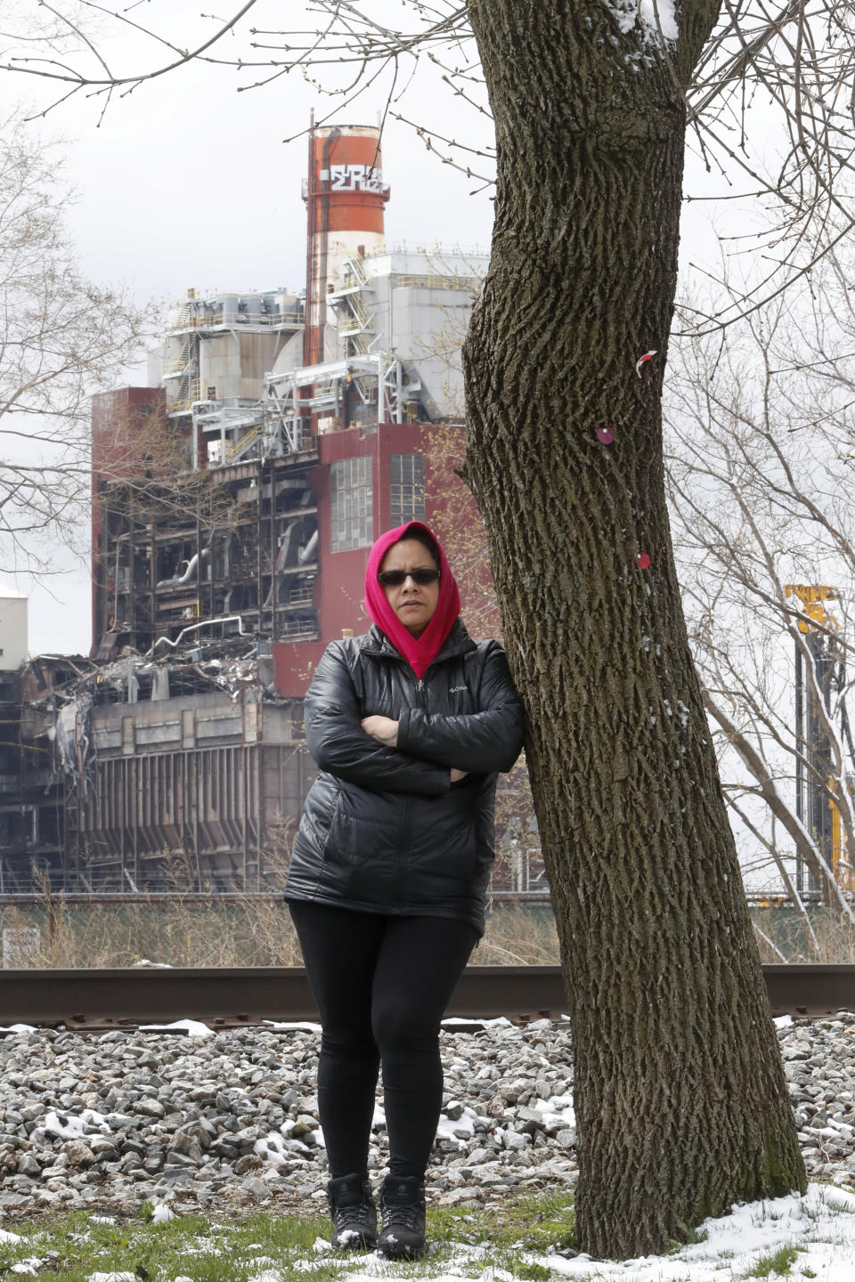 In this Wednesday, April 15, 2020, photo, Kim Wasserman with the Little Village Environmental Justice Organization in Chicago, poses near the Crawford Coal Plant, the last of the city's coal power plants, where demolition is ongoing. Demolition of an old smokestack at a former coal-fired power plant recently sent a cloud of ash into the neighborhood. The low-income, Hispanic community also is concerned that plans for a logistics and transportation hub will bring more diesel pollution to the neighborhood. Communities of color are still disproportionately affected by pollution 50 years after the first Earth Day. (AP Photo/Charles Rex Arbogast)