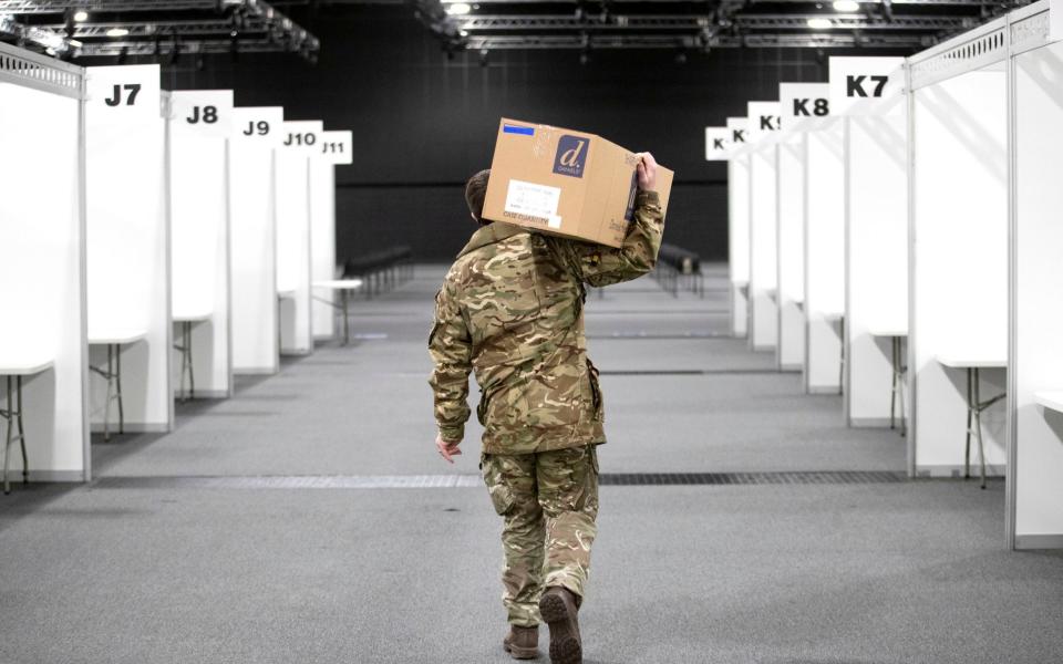 A member of the Royal Scots Dragoon Guard carries in supplies as part of the final preparations setting up a mass covid vaccination centre at the P and J Live Arena in Aberdeen - PA