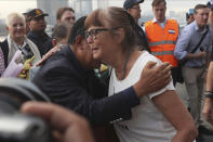 A passenger, right, is hugged by Cambodia Prime Minister Hun Sen after she disembarked from the MS Westerdam, owned by Holland America Line, at the port of Sihanoukville, Cambodia, Friday, Feb. 14, 2020. Passengers finally disembarked on Friday from the cruise ship allowed to dock in Cambodia following two weeks of being stranded at sea after being refused entry by four Asian governments because of virus fears. (AP Photo/Heng Sinith)