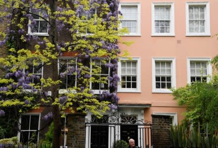 A man walks past the exterior of a house covered in blooming wisteria in west London, Britain, April 28, 2018. REUTERS/Toby Melville