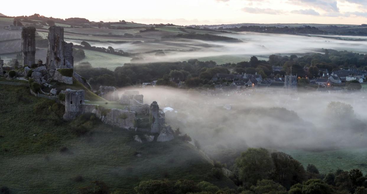 A low lying mist surrounds the village of Corfe Castle in Dorset on the day of the Autumn Equinox (Andrew Matthews/PA)