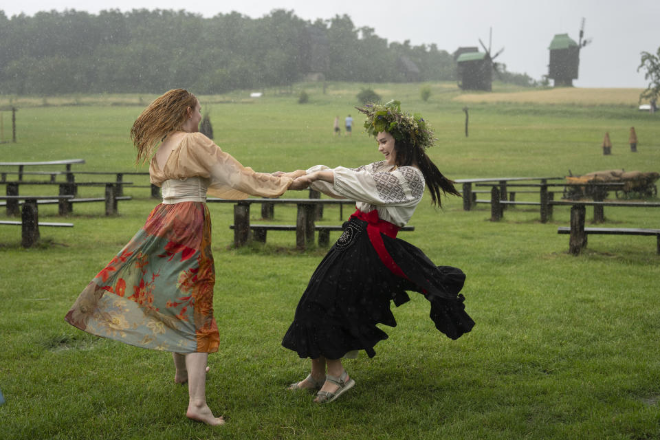 Ukrainian young women dressed in traditional clothing dance under heavy rain at a traditional Midsummer Night celebration near capital Kyiv, Ukraine, Sunday, June 23, 2024. The age-old pagan festival is still celebrated in Ukraine amid the third year of Russia-Ukraine war. (AP Photo/Efrem Lukatsky)