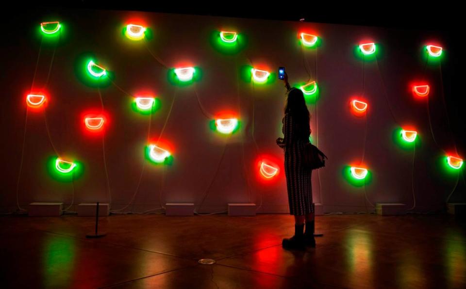 Lily Reeves, an artist from Phoenix, Arizona, snaps a photo of Jude Abu Zaineh’s “Tend to Grow” art piece during the “She Bends: Redefining Neon Legacy” art exhibit at the Museum of Glass in downtown Tacoma, Washington, on Saturday, Feb. 11, 2023. Reeves was at the exhibit to display her neon artwork “Room to Breath.”