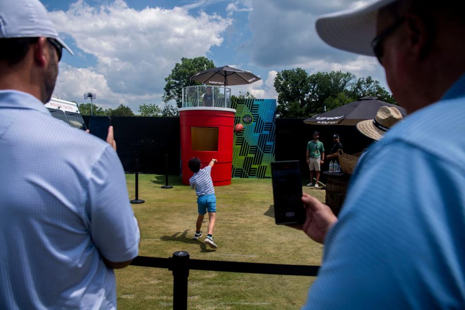 George Caudill, 6, throws a football to the dunk tank while Ben Caudill records during the LIV Golf Tournament at The Grove near Franklin, Tenn., Friday, June 21, 2024.