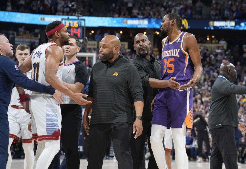 Security officials step between Denver Nuggets forward Bruce Brown, left, and Phoenix Suns forward Kevin Durant, who exchange words after Brown and teammate Nikola Jokic tried to listen as the Suns huddled during a timeout in the second half of Game 5 of an NBA Western Conference basketball semifinal playoff series Tuesday, May 9, 2023, in Denver. (AP Photo/David Zalubowski)