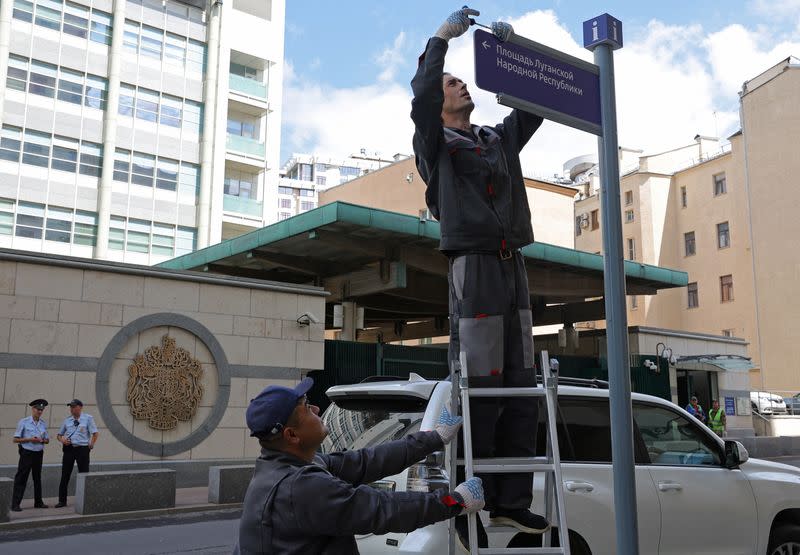 Workers install a direction sign "Luhansk People's Republic Square" in front of the British embassy in Moscow