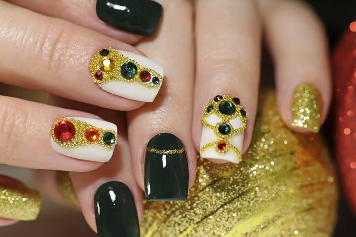 new years fashionable beautiful festive manicure on short square nails with green lacquer color, with golden sequins, bouillon and rhinestones of different colors christmas nail art