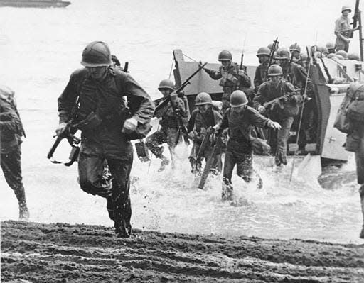 U.S. Marines, with full battle kits, charge ashore on Guadalcanal Island from a landing barge during the early phase of the U.S. offensive in the Solomon Islands in Aug. 1942 during World War II.