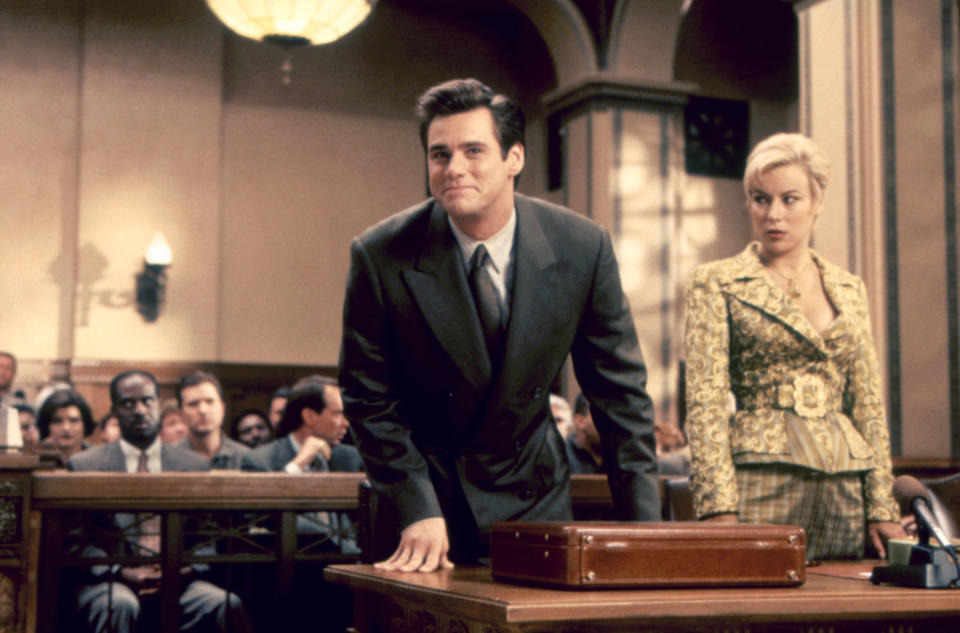 Jim Carrey and Jennifer Tilly stand behind a courtroom table