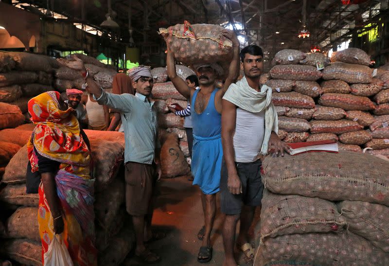 FILE PHOTO: Labourer carries sack of onions at wholesale market in Kolkata