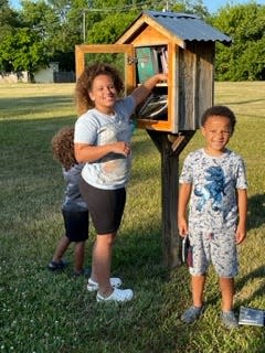 From left: Azar Laidler, Kendall Williams and Armani Laidler help stock small free libraries with books.
