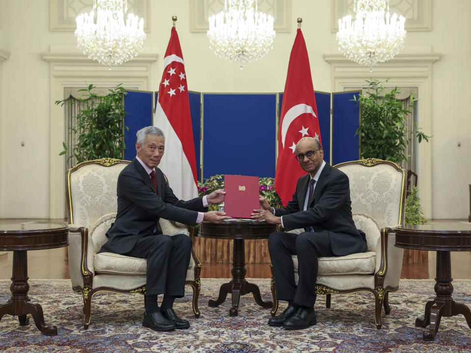 In this photo released by Singapore's Ministry of Communications and Information, Singapore President Tharman Shanmugaratnam, right, receives a letter of intent to resign from Singapore's Prime Minister Lee Hsien Loong at the Istana in Singapore, Monday, May 13, 2024. (Mohd Fyrol/Ministry of Communications and Information via AP)