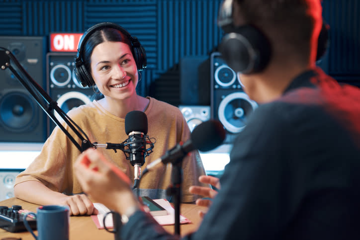 Two radio show hosts conversing on-air in a studio with microphones and headphones