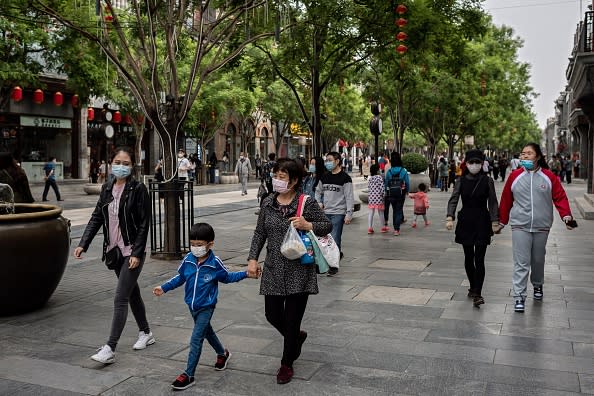 People wearing face masks as a preventive measure against the COVID-19 coronavirus walk on a street in Beijing.