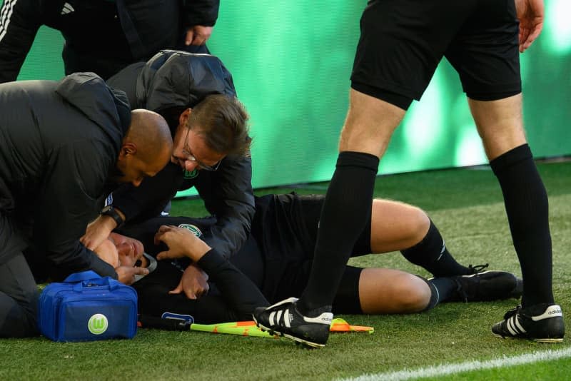 Assistant referee Thorben Siewer lies injured on the ground during the German Bundesliga soccer match between VfL Wolfsburg and FC Cologne at Volkswagen Arena. Swen Pförtner/dpa