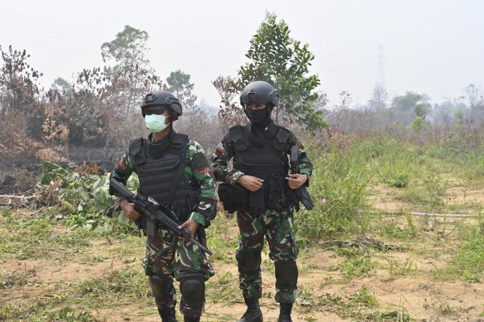 Indonesian soldiers walk next to a burnt peatland following a fire in Kampar, Riau province September 17, 2019. — AFP pic