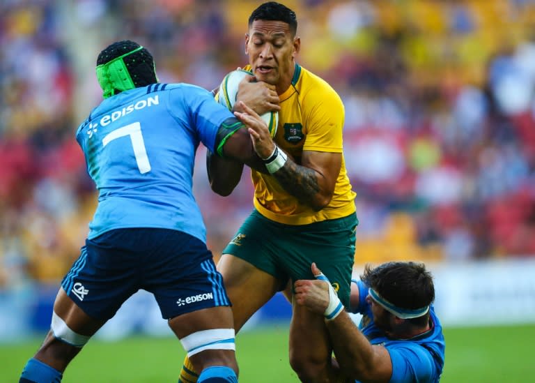 Israel Folau (C) of Australia is tackled by Italy's Maxime Mbandao (L) and Marco Fuser during their rugby union Test match at Suncorp Stadium in Brisbane on June 24, 2017