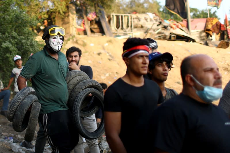 An Iraqi demonstrator carries tires during the ongoing anti-government protests in Baghdad